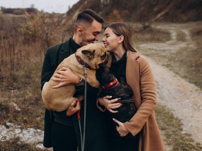 Young couple walking their french bulldogs in park